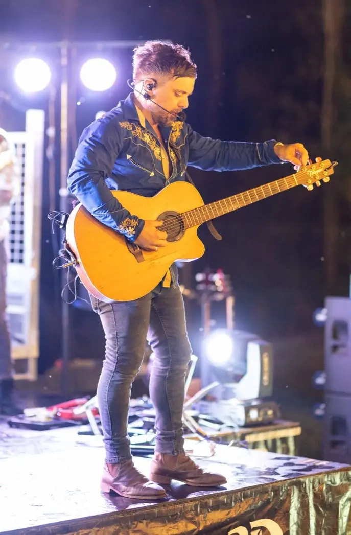Laurence Sorbello playing acoustic guitar on stage