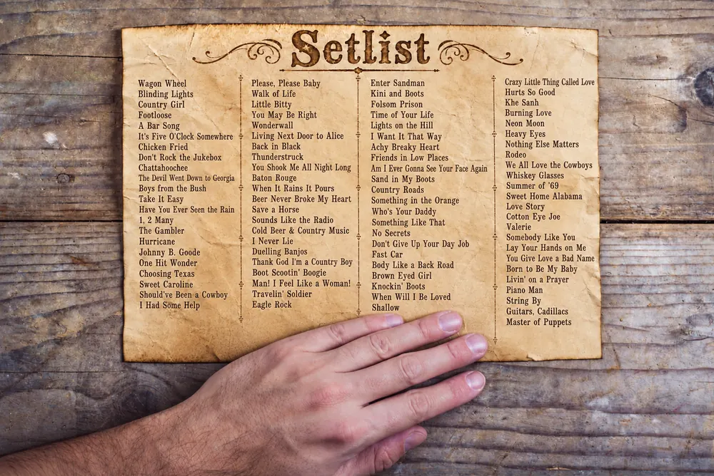 The Barnyard Band set list on an aged parchment page, held flat on a timber table